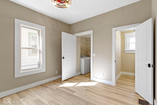 unfurnished bedroom with washer / dryer, visible vents, baseboards, and light wood-type flooring