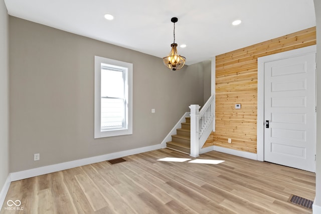 foyer featuring stairs, wooden walls, visible vents, and light wood finished floors