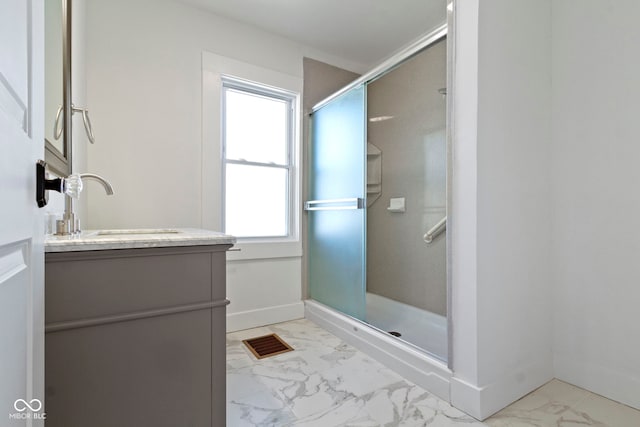 bathroom featuring marble finish floor, vanity, a shower stall, and baseboards