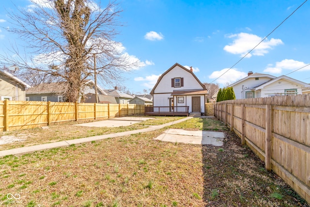 rear view of house with an outbuilding, a patio, a fenced backyard, a gambrel roof, and a lawn