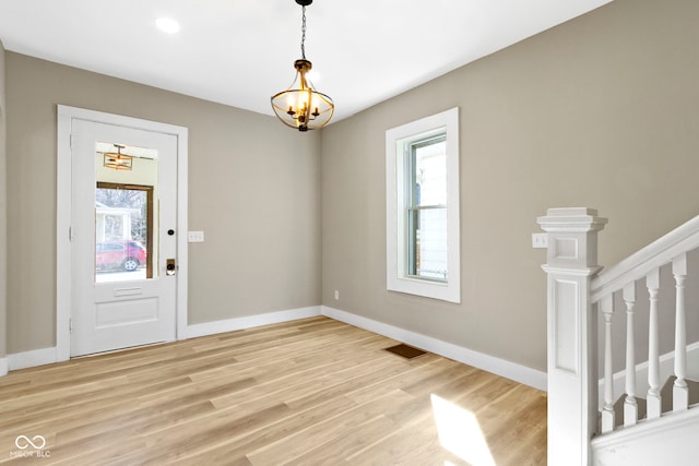 foyer featuring a notable chandelier, visible vents, light wood-type flooring, and baseboards