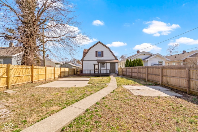 rear view of property featuring an outdoor structure, a patio area, a gambrel roof, and a fenced backyard