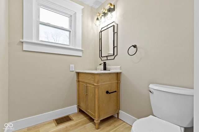 bathroom featuring toilet, wood finished floors, visible vents, and baseboards