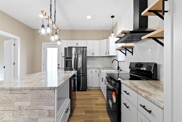 kitchen featuring black range with electric stovetop, white cabinets, stainless steel fridge, wall chimney exhaust hood, and a sink