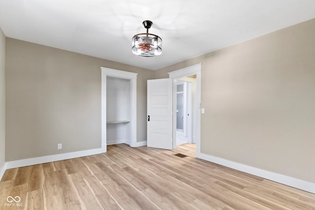 empty room featuring light wood-type flooring, baseboards, and visible vents