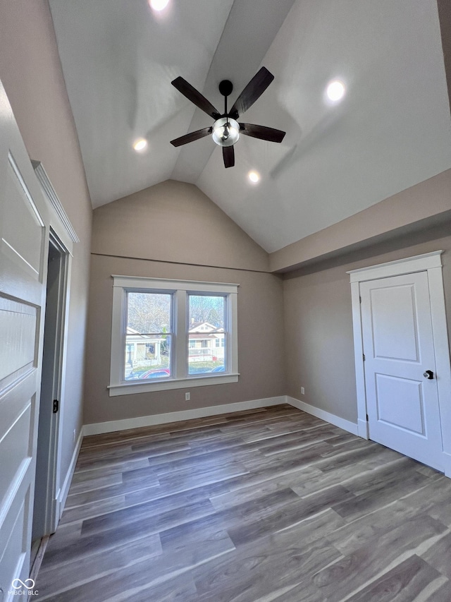 unfurnished bedroom featuring baseboards, lofted ceiling, and wood finished floors