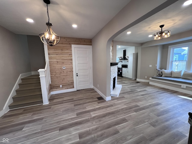 foyer featuring wood finished floors, recessed lighting, arched walkways, wooden walls, and stairs