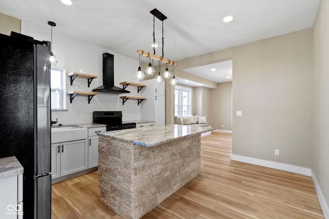 kitchen with decorative backsplash, light wood-style flooring, appliances with stainless steel finishes, exhaust hood, and open shelves