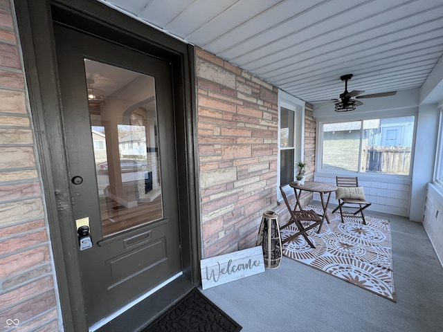 property entrance featuring brick siding, a ceiling fan, and covered porch