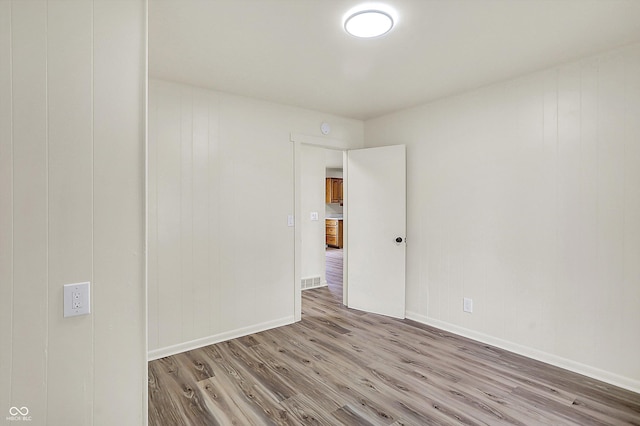 empty room featuring visible vents, baseboards, and wood finished floors