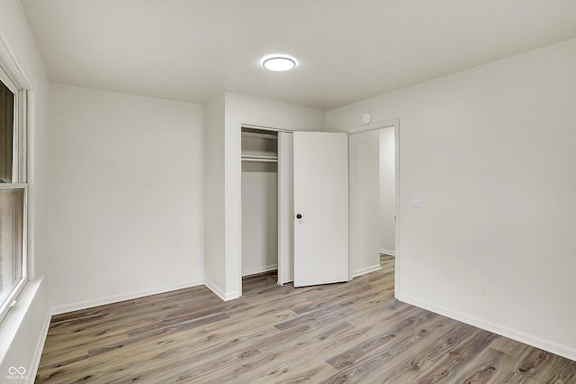 unfurnished bedroom with a closet, baseboards, and wood finished floors