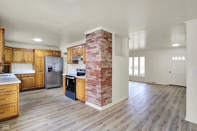 kitchen featuring under cabinet range hood, light countertops, light wood-type flooring, electric range oven, and stainless steel fridge