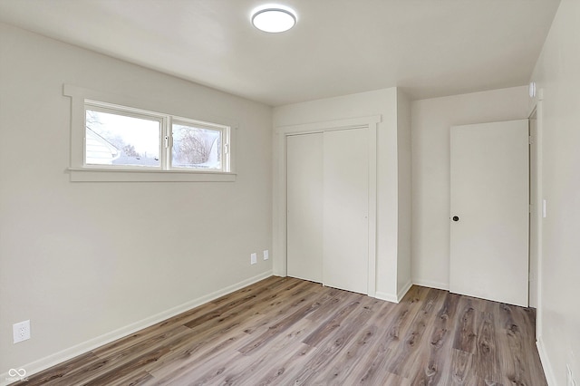 unfurnished bedroom featuring a closet, baseboards, and wood finished floors