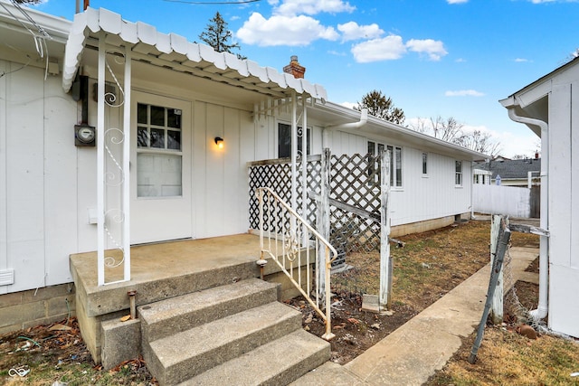 entrance to property featuring a chimney and a porch