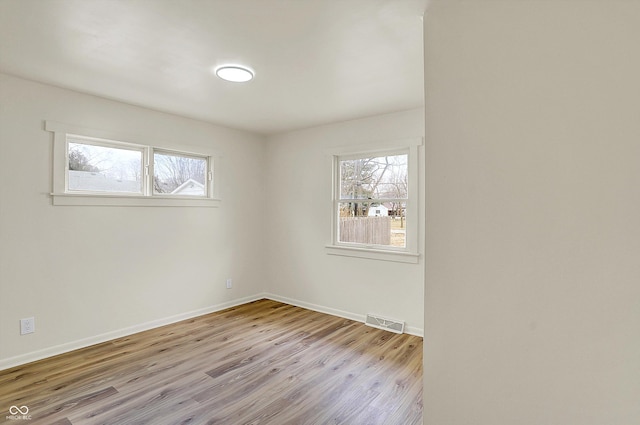 spare room featuring baseboards, visible vents, and wood finished floors