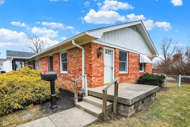 view of front of house featuring a front yard, a gate, brick siding, and fence