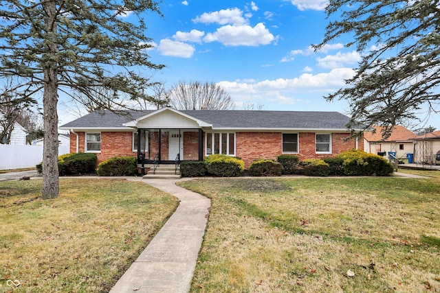 single story home featuring a shingled roof, brick siding, fence, and a front lawn