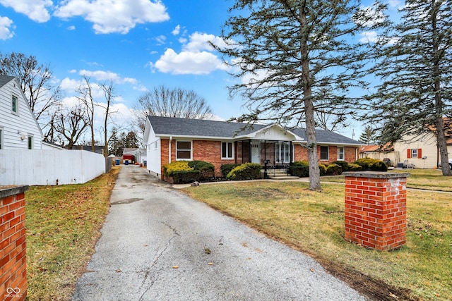 ranch-style home with driveway, brick siding, a front yard, and fence