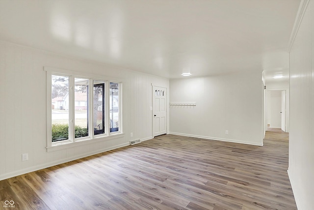 spare room featuring wood finished floors, visible vents, and baseboards