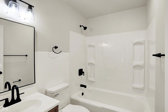 full bathroom with toilet,  shower combination, tile walls, and vanity