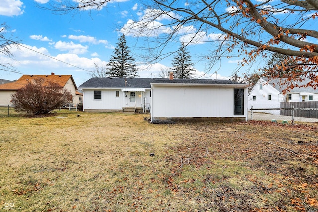 back of house featuring entry steps, fence private yard, a chimney, and a yard