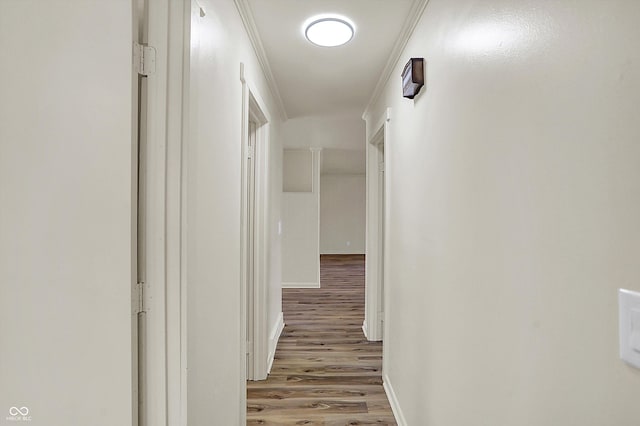 hall with crown molding, light wood-style flooring, and baseboards