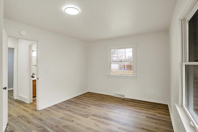 spare room with light wood-style flooring, visible vents, and baseboards