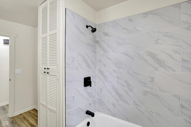 full bath featuring baseboards, tub / shower combination, and wood finished floors