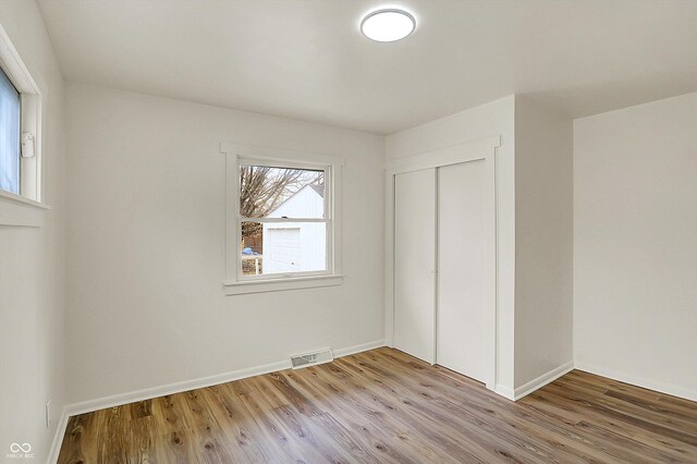 unfurnished bedroom with light wood finished floors, a closet, visible vents, and baseboards