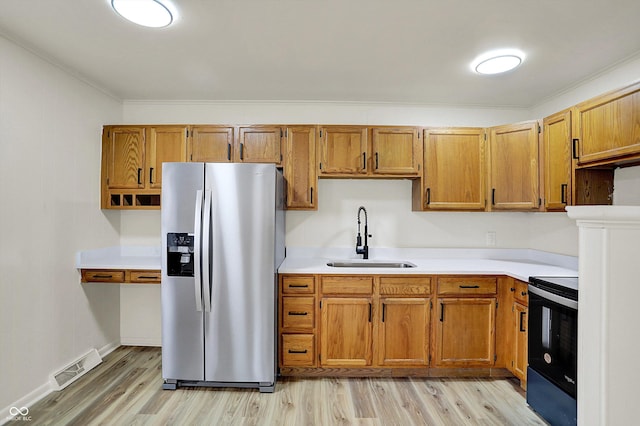 kitchen with light wood-style flooring, range with electric stovetop, a sink, visible vents, and stainless steel fridge