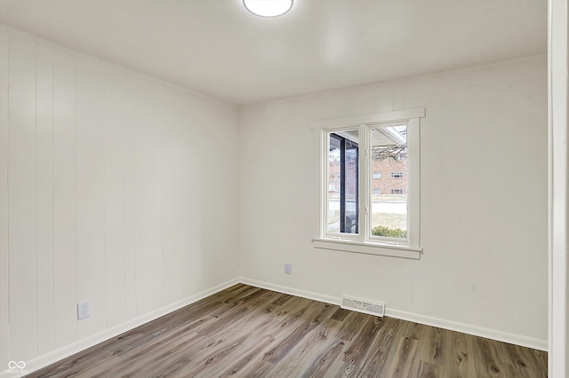 empty room featuring baseboards, visible vents, and wood finished floors