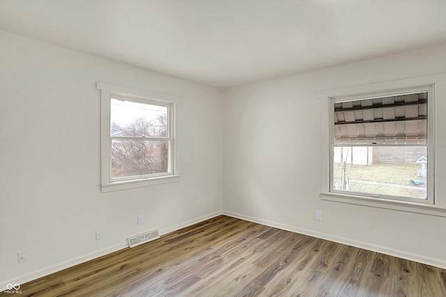 spare room featuring baseboards, visible vents, and wood finished floors