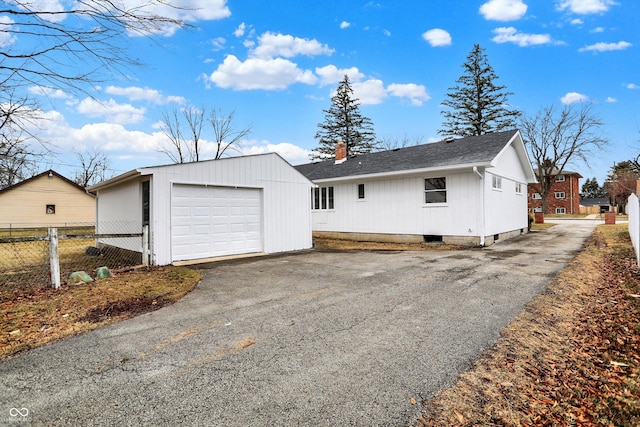 exterior space with an outbuilding, fence, driveway, roof with shingles, and a chimney