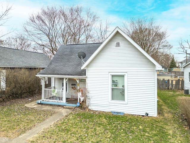 rear view of property with a shingled roof, covered porch, fence, a yard, and central air condition unit