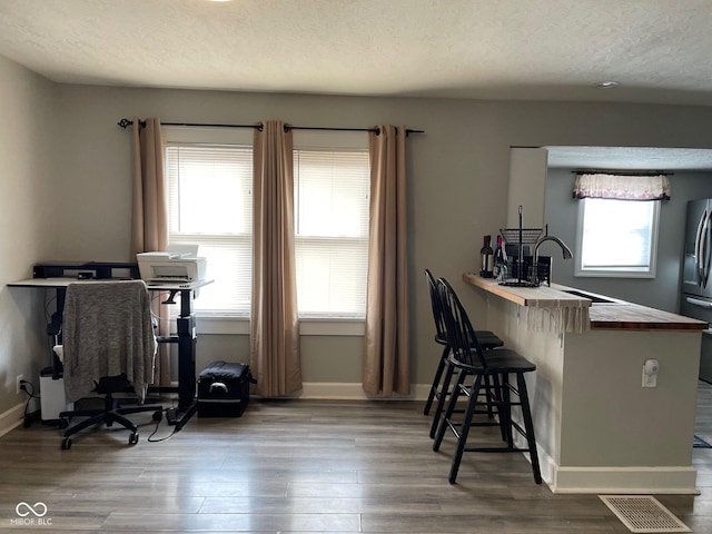 interior space featuring visible vents, a sink, a textured ceiling, and wood finished floors