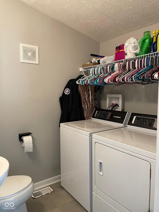 washroom featuring laundry area, visible vents, baseboards, a textured ceiling, and washing machine and dryer