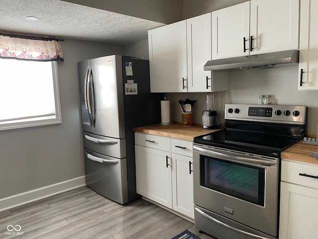 kitchen with appliances with stainless steel finishes, butcher block countertops, light wood-style floors, and under cabinet range hood