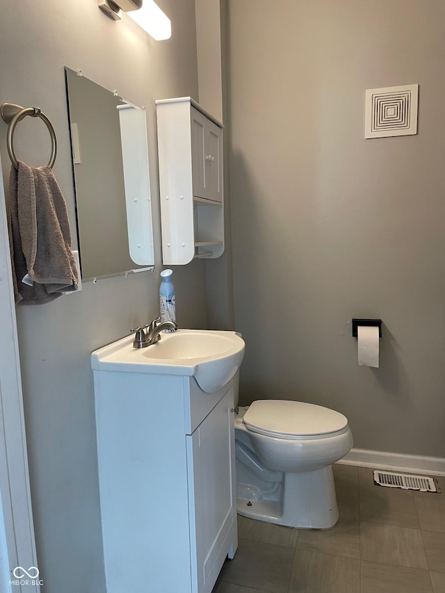 half bathroom featuring baseboards, visible vents, toilet, tile patterned flooring, and vanity