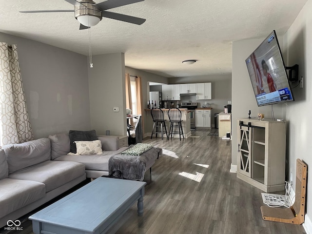 living room with ceiling fan, dark wood-style flooring, and a textured ceiling