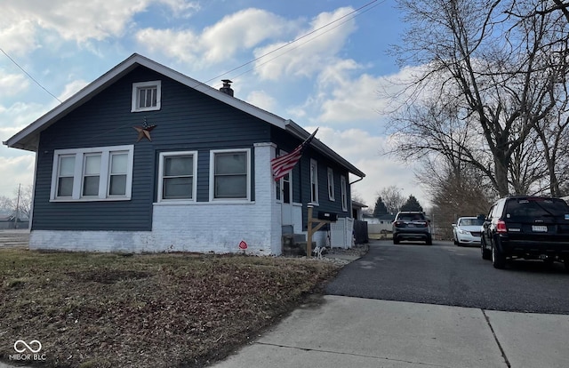 view of property exterior with aphalt driveway, brick siding, and a chimney