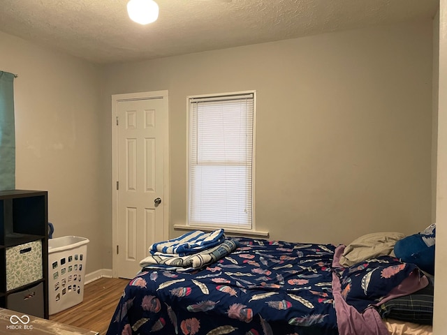 bedroom with a textured ceiling and wood finished floors