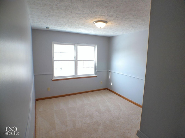 unfurnished room with light carpet, a textured ceiling, and baseboards