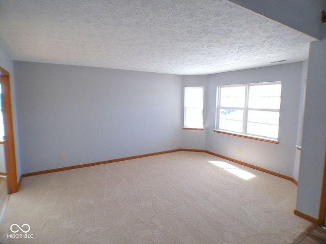 unfurnished room with carpet, baseboards, and a textured ceiling