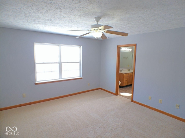 spare room featuring baseboards, a textured ceiling, and light colored carpet