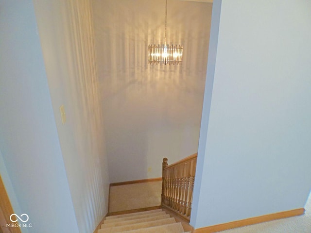 stairway featuring a notable chandelier and baseboards