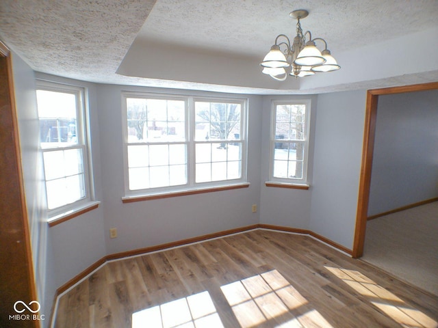 interior space featuring a textured ceiling, a chandelier, wood finished floors, and baseboards