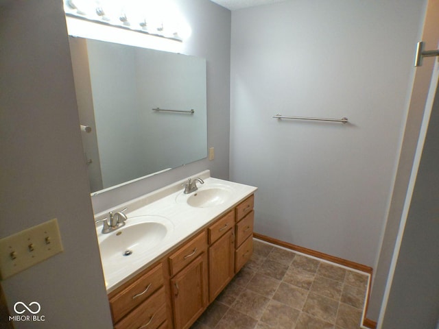 bathroom with double vanity, baseboards, and a sink