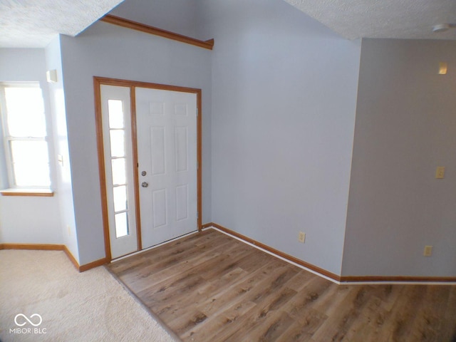 foyer entrance with a textured ceiling, wood finished floors, and baseboards