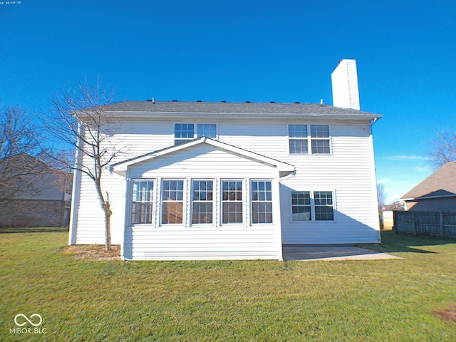 rear view of house featuring a chimney, fence, a lawn, and a patio