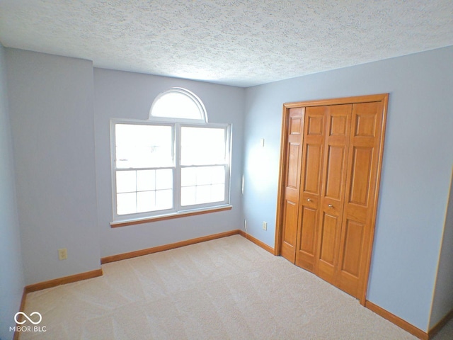 unfurnished bedroom featuring a textured ceiling, baseboards, and carpet flooring